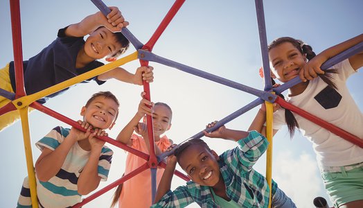 Portrait of happy schoolkids looking through dome climber